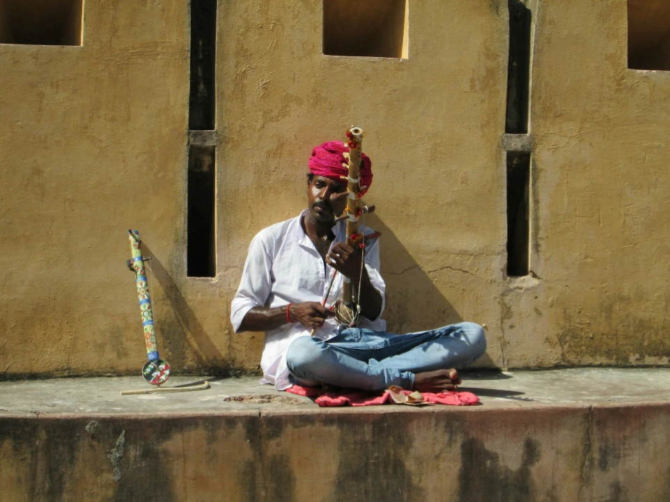 man in white shirt playing guitar sitting on red textile